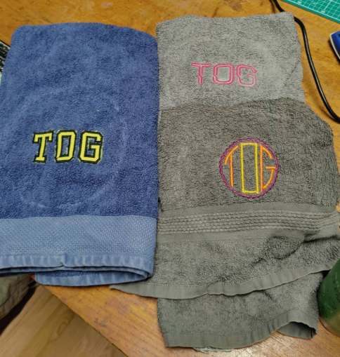 Three towels with the word Tog embroidered in various fonts