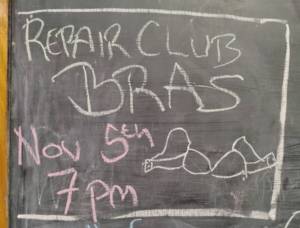 A blackboard notice about Repair Club for Bras on Nov 5th at 7pm with a drawing of a bra