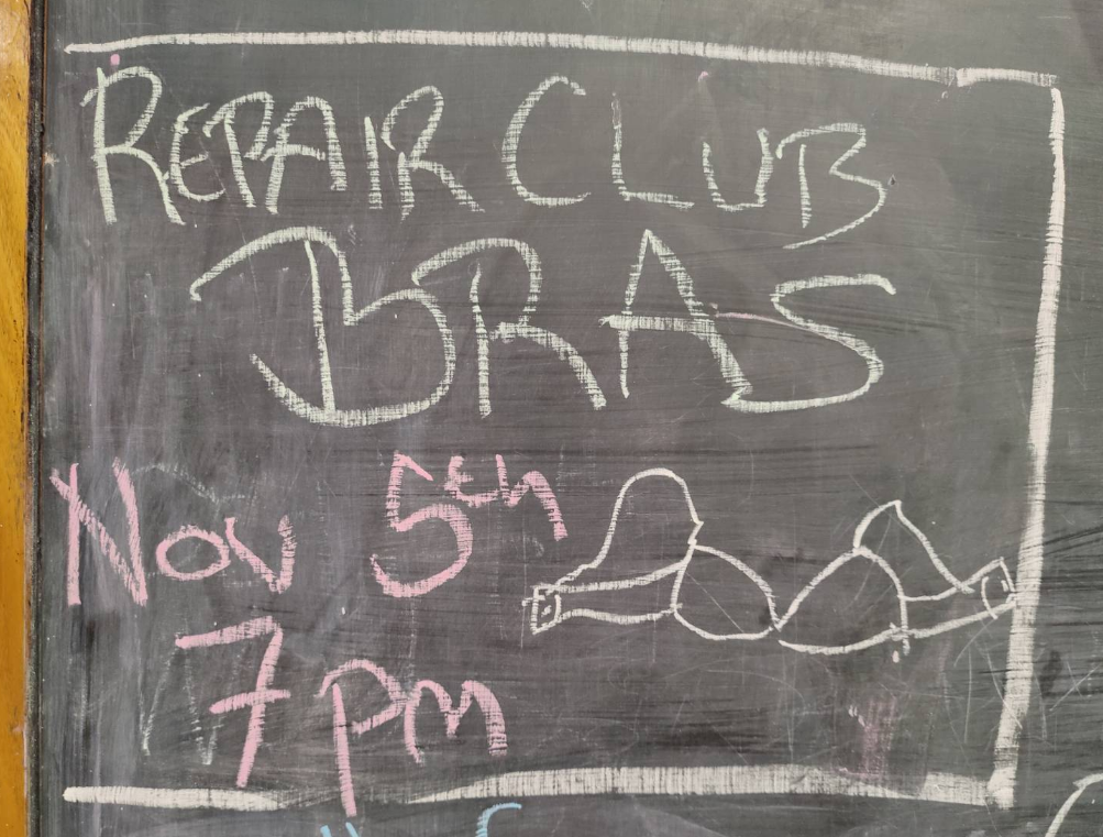 A blackboard notice about Repair Club for Bras on Nov 5th at 7pm with a drawing of a bra